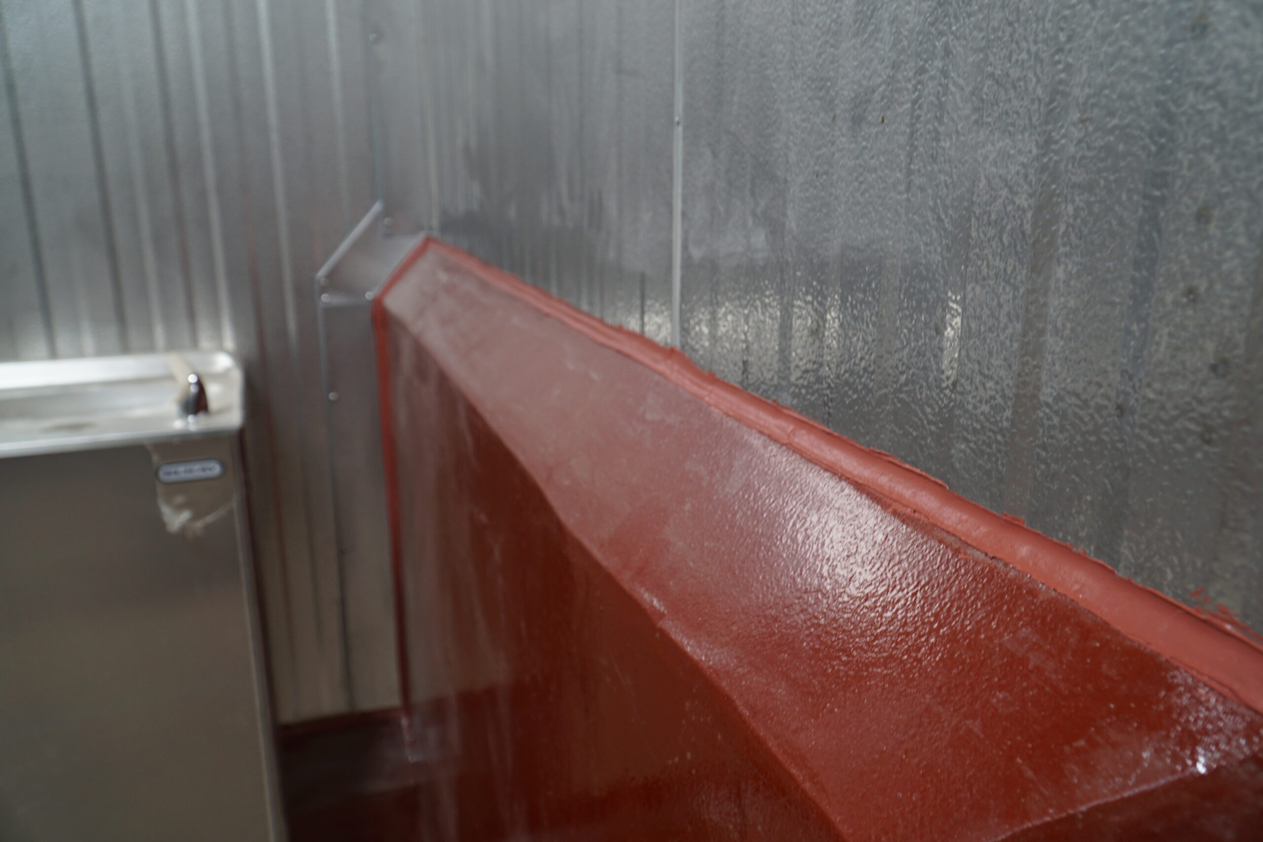 Red caulk on concrete & metal wall